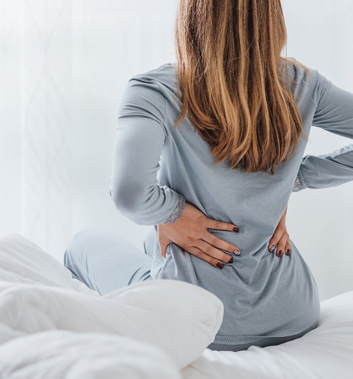 Woman with lower back pain, may benefit from prolotherapy