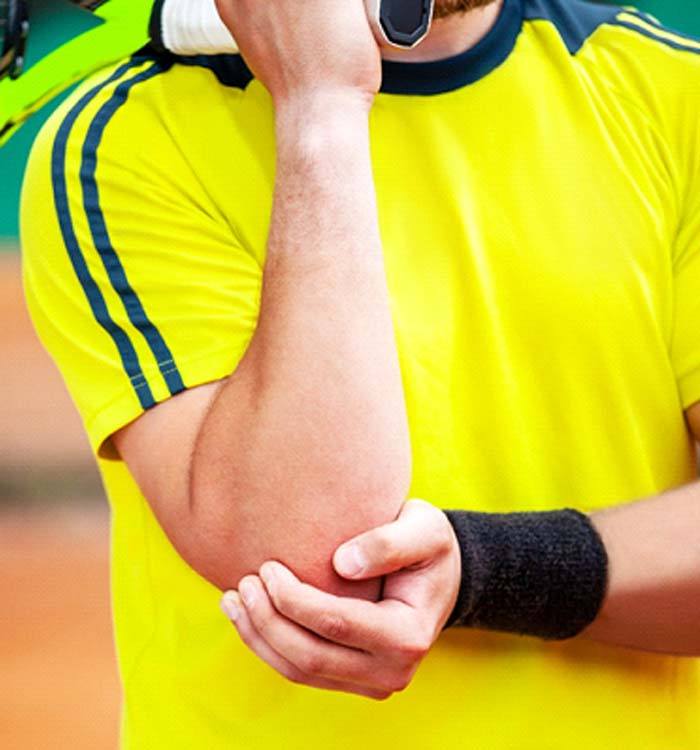 man bracing elbow on court due to Tennis Elbow
