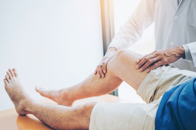 Doctor performing osteopathic manipulative therapy on patient’s leg