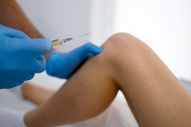 Doctor administering injection in patient’s knee