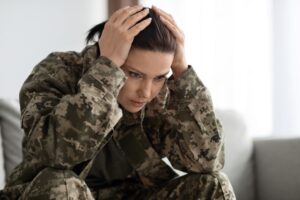 Female soldier, sitting on sofa and struggling with PTSD anxiety