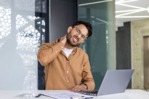 Man dealing with neck pain while sitting at computer